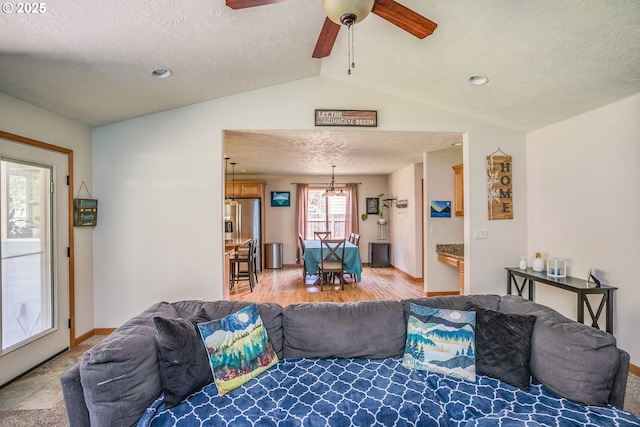 living room featuring lofted ceiling, a ceiling fan, a textured ceiling, baseboards, and light wood-style floors