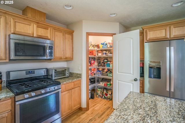 kitchen featuring stainless steel appliances, light wood-style floors, light stone countertops, and recessed lighting