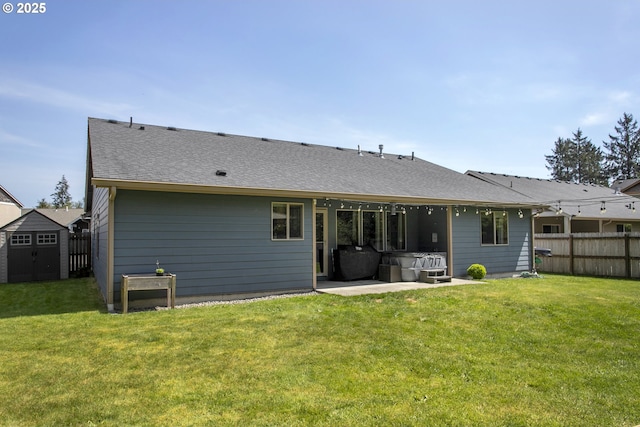back of house featuring a hot tub, a patio, a storage shed, an outbuilding, and a shingled roof