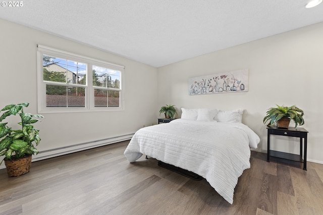 bedroom featuring baseboard heating, a textured ceiling, and hardwood / wood-style flooring