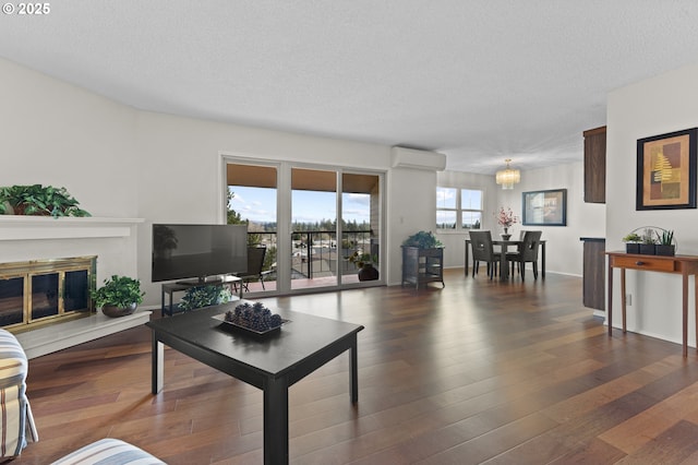 living room featuring a notable chandelier, dark hardwood / wood-style flooring, a textured ceiling, and a wall mounted AC