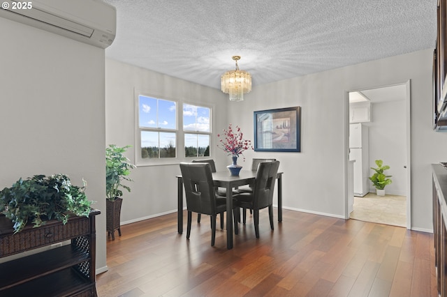 dining space featuring a wall unit AC, dark wood-type flooring, a chandelier, and a textured ceiling