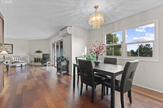 dining space with a textured ceiling, dark wood-type flooring, a wall unit AC, and an inviting chandelier