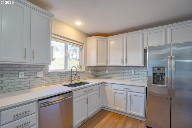 kitchen featuring stainless steel appliances, sink, white cabinets, and decorative backsplash