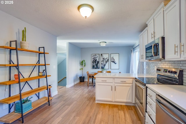 kitchen with appliances with stainless steel finishes, light hardwood / wood-style flooring, decorative backsplash, and white cabinets