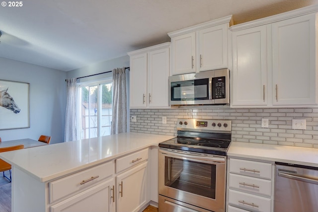 kitchen with stainless steel appliances, white cabinetry, tasteful backsplash, and kitchen peninsula