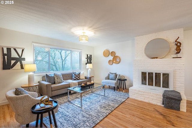 living room featuring a brick fireplace and wood-type flooring