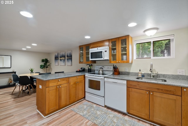 233 SE 28th Ave, Portland, OR 97214 - kitchen with white appliances, a sink, a peninsula, light wood finished floors, and brown cabinetry