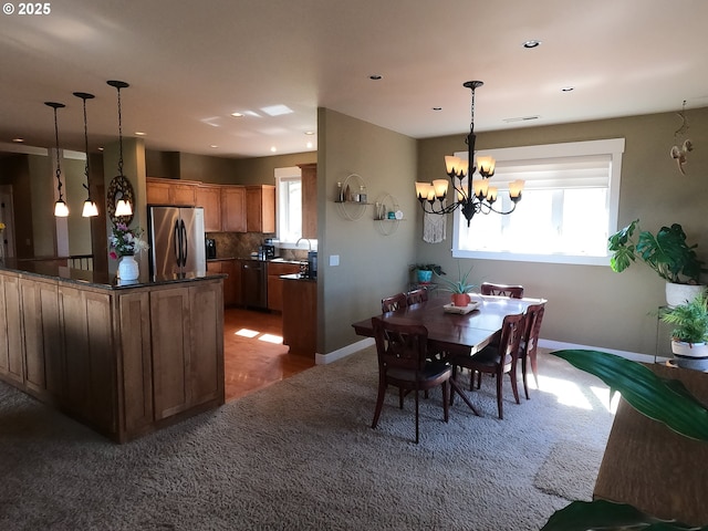 dining space featuring carpet, baseboards, and a notable chandelier