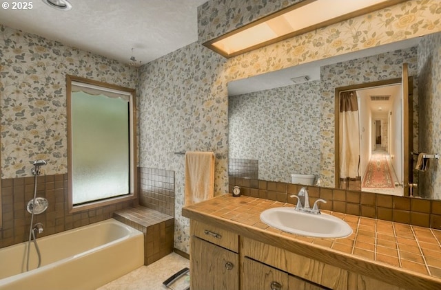 full bathroom featuring a bath, wallpapered walls, vanity, and tile patterned floors