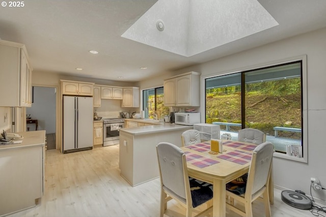 kitchen with white appliances, a sink, light wood-style floors, light countertops, and recessed lighting
