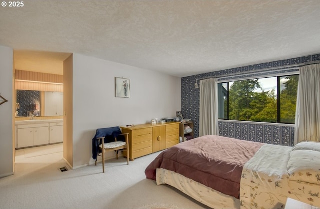 bedroom with carpet, baseboards, ensuite bathroom, and a textured ceiling