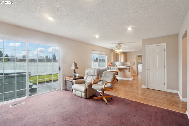 sitting room featuring light colored carpet, a ceiling fan, baseboards, light wood-style floors, and visible vents