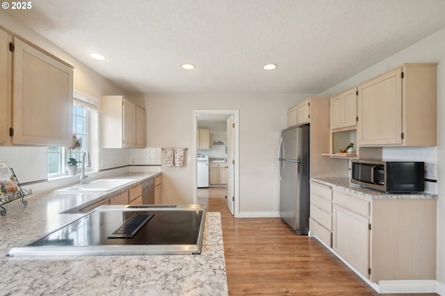 kitchen with decorative backsplash, stainless steel appliances, light countertops, separate washer and dryer, and a sink