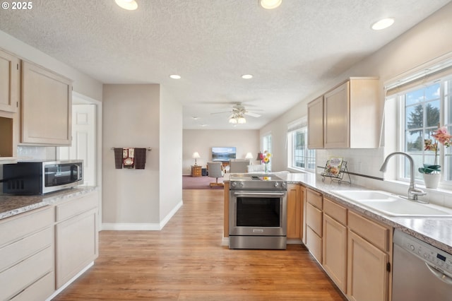 kitchen featuring stainless steel appliances, light wood-type flooring, a sink, and backsplash