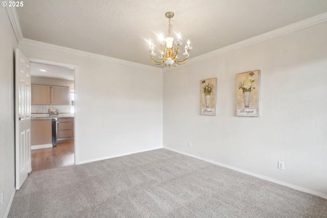 unfurnished room featuring a chandelier, a textured ceiling, carpet flooring, baseboards, and ornamental molding