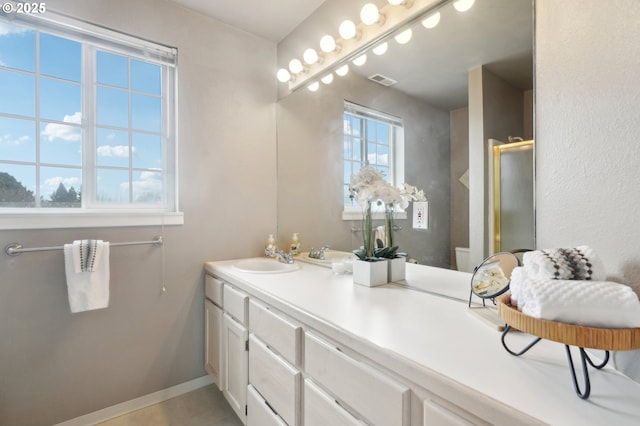 bathroom with toilet, vanity, visible vents, baseboards, and a stall shower