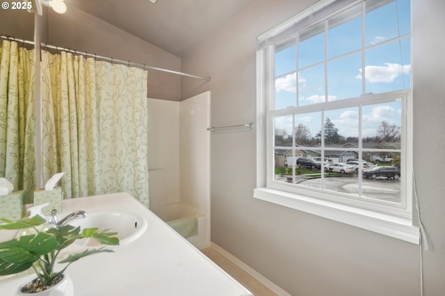 bathroom with vaulted ceiling, shower / bathtub combination with curtain, baseboards, and vanity