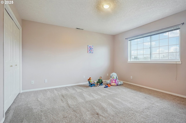 playroom with a textured ceiling, carpet floors, visible vents, and baseboards