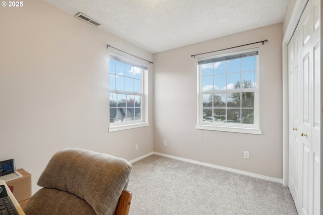 sitting room with baseboards, carpet, visible vents, and a textured ceiling