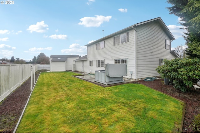 rear view of house featuring an outdoor structure, a fenced backyard, a deck, and a yard