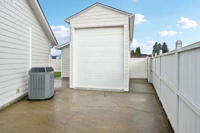 detached garage with central air condition unit, driveway, and fence