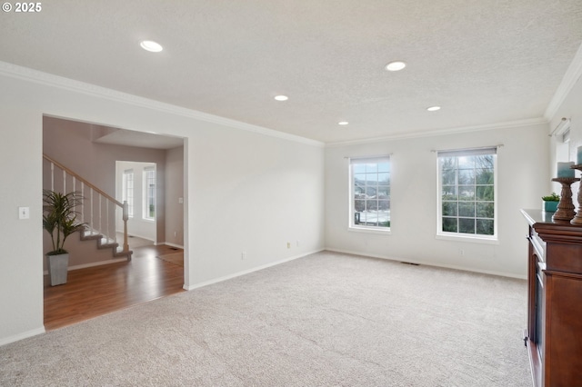 unfurnished room with ornamental molding, carpet, a textured ceiling, and stairs