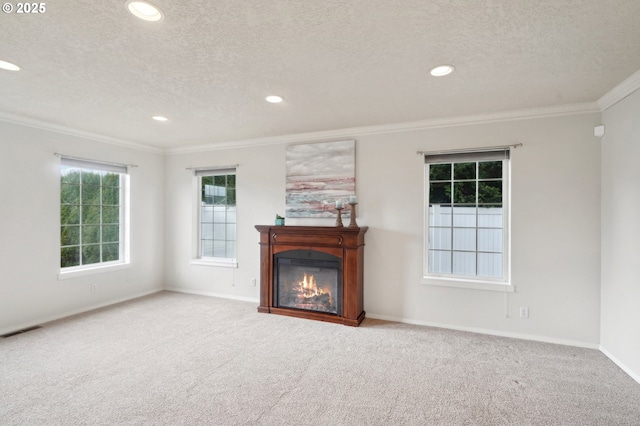 unfurnished living room with carpet floors, a glass covered fireplace, visible vents, and ornamental molding