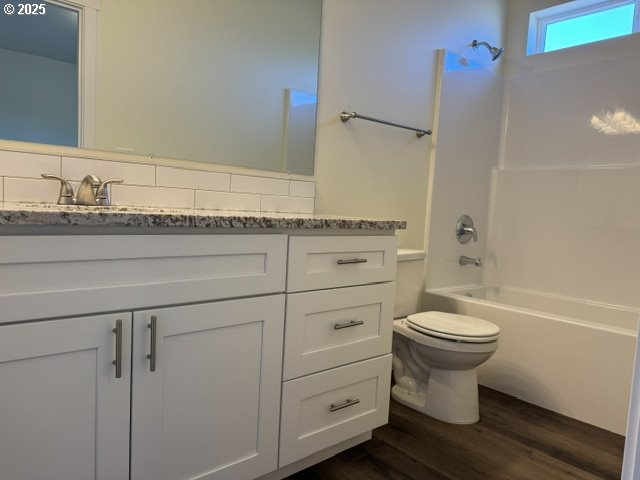 full bathroom with vanity, toilet, wood-type flooring, and bathtub / shower combination