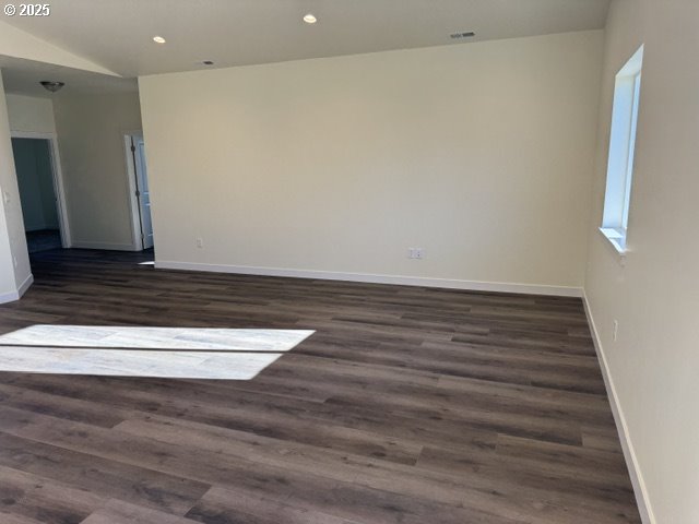 spare room with dark hardwood / wood-style floors and vaulted ceiling