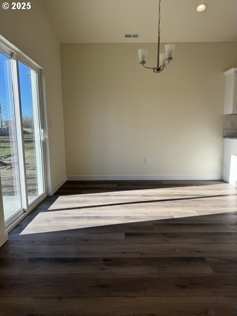 unfurnished dining area featuring dark hardwood / wood-style flooring and a notable chandelier