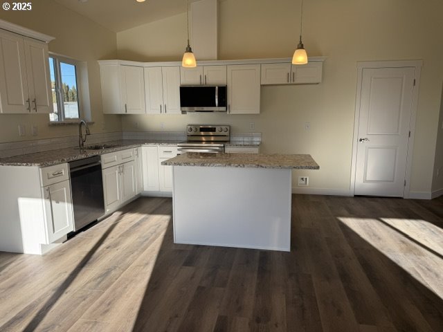 kitchen featuring decorative light fixtures, a kitchen island, white cabinetry, and stainless steel appliances