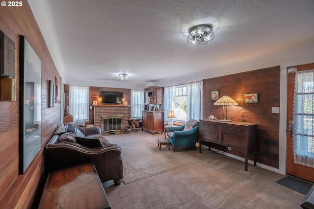 living room with wooden walls, carpet floors, a textured ceiling, and a fireplace