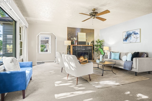 1422 NE 57th Ave, Portland, OR 97213 - carpeted living area featuring a fireplace, a textured ceiling, a ceiling fan, and arched walkways
