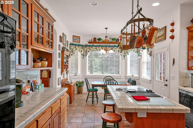 83485 Clear Lake Rd, Florence, OR 97439 - kitchen with tile counters, recessed lighting, black dishwasher, glass insert cabinets, and brown cabinetry