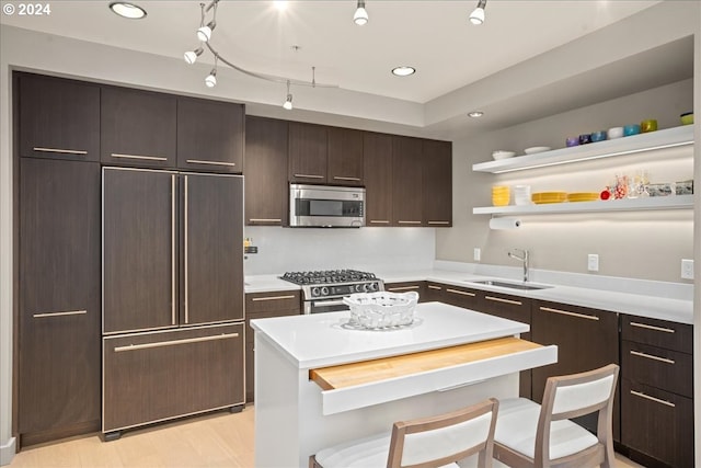 kitchen featuring sink, dark brown cabinetry, a kitchen breakfast bar, track lighting, and stainless steel appliances