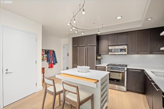 kitchen featuring light hardwood / wood-style floors, stainless steel appliances, sink, dark brown cabinetry, and a center island