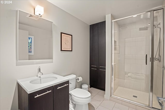 bathroom with toilet, tile patterned flooring, a shower with door, and vanity