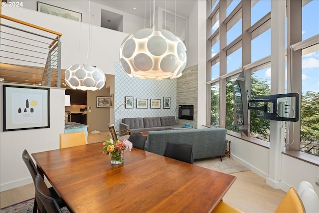 dining area with light wood-type flooring, a fireplace, and plenty of natural light