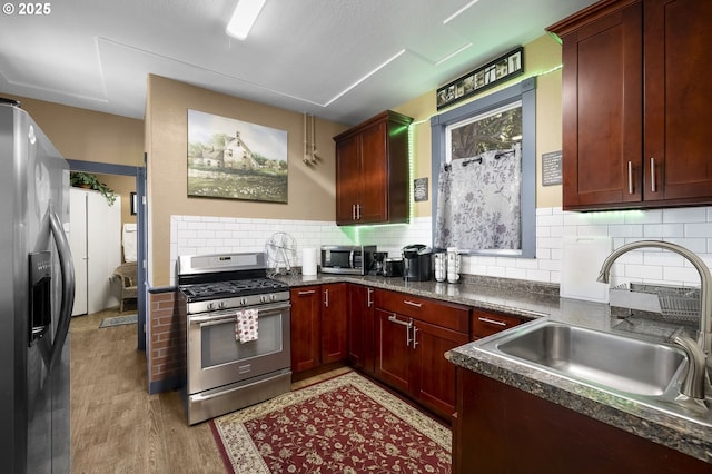 kitchen featuring sink, decorative backsplash, light wood-type flooring, and appliances with stainless steel finishes