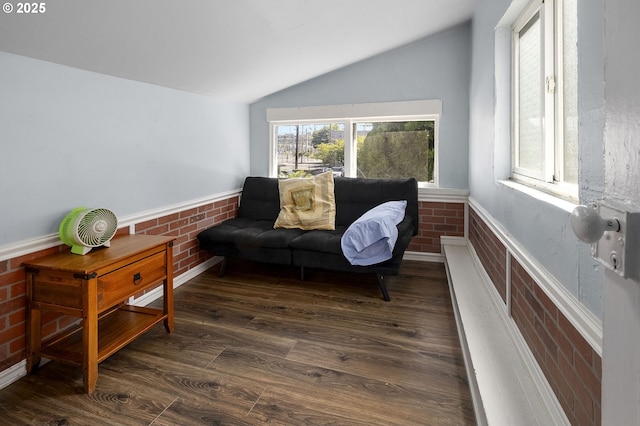 living area with lofted ceiling, brick wall, and dark hardwood / wood-style flooring