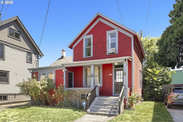 front facade with cooling unit, a front lawn, and covered porch