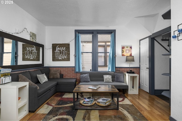 living room with hardwood / wood-style flooring, plenty of natural light, and brick wall