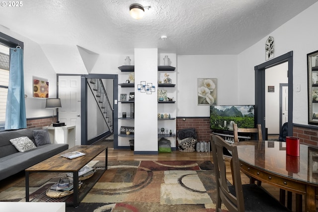 living room with lofted ceiling, brick wall, dark hardwood / wood-style floors, and a textured ceiling