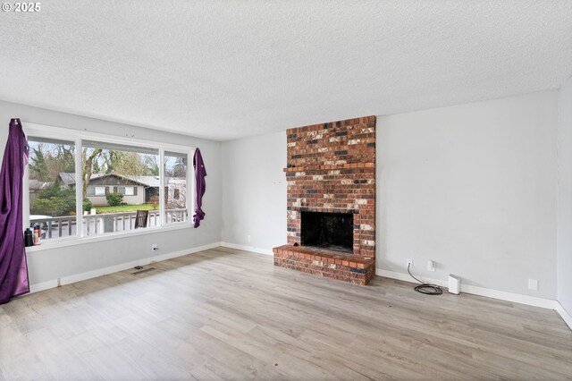 4973 Wagon Trail Ct, Salem, OR 97317 - unfurnished living room featuring wood finished floors, a textured ceiling, a brick fireplace, and baseboards