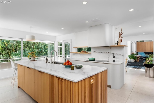 kitchen featuring sink, white cabinetry, a center island with sink, and tasteful backsplash