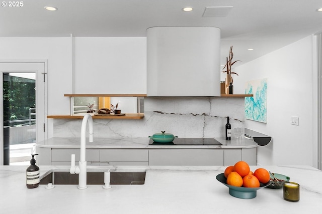 kitchen with decorative backsplash, sink, white cabinetry, and black electric stovetop