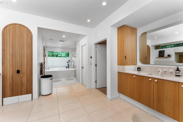 bathroom featuring tiled bath, tile patterned floors, and vanity