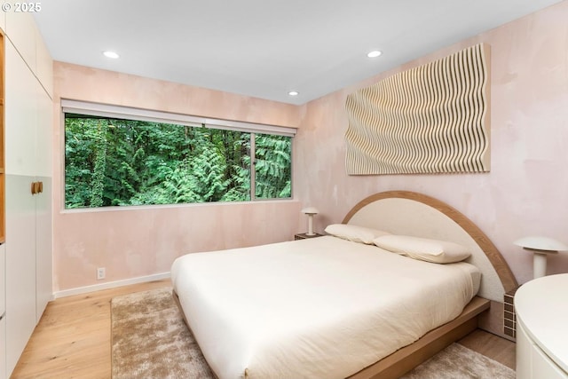 bedroom with light hardwood / wood-style floors and multiple windows