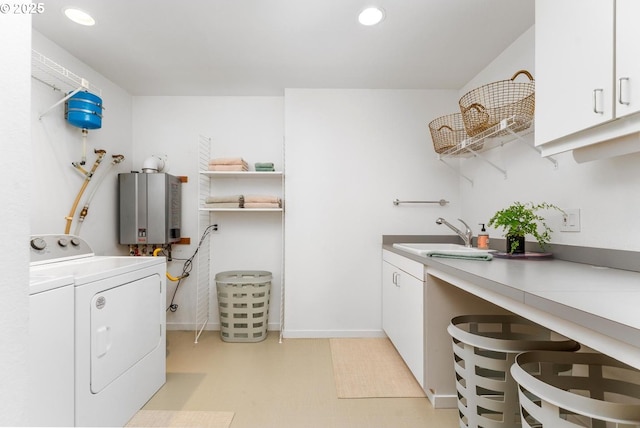 clothes washing area with washing machine and dryer, tankless water heater, sink, and cabinets